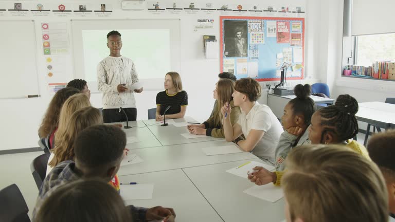 Junior high students clapping for student giving debate club presentation in classroom. MS, real time.