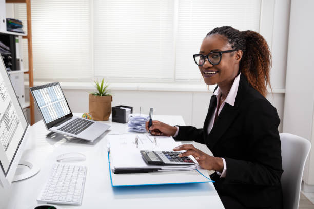 Happy Young Businesswoman Calculating Invoice On Computer Screen Near Laptop