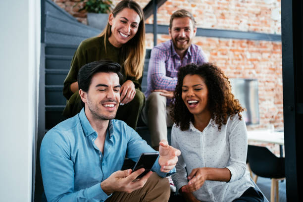 Multi-ethnic group of young people sitting on the stairs and using smartphones.