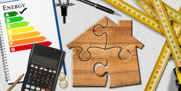 Home improvement concept - Wooden ruler in the shape of a house with energy efficiency rating on a blackboard with work tools and a light bulb