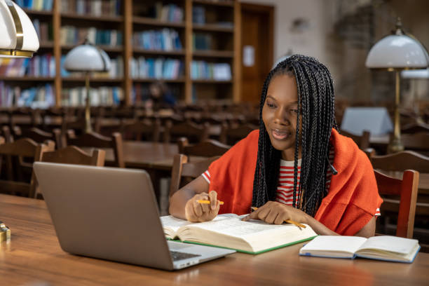Woman studying. Long-haired young woman in red clothes studying in the library