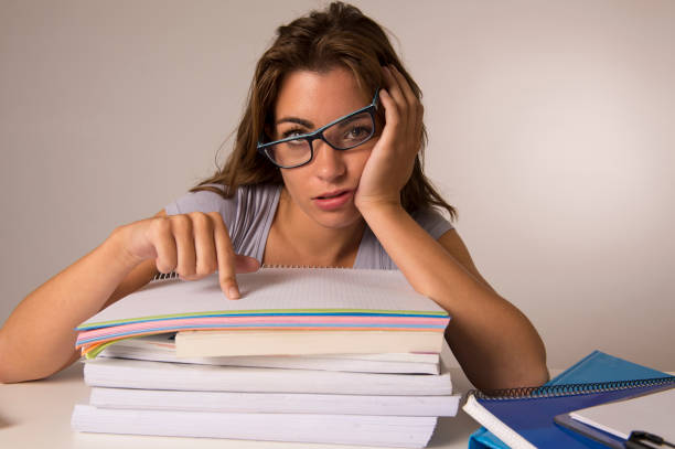 young attractive and beautiful tired student girl leaning on school books pile tired and exhausted after studying preparing exam looking wasted taking a nap in stress education concept