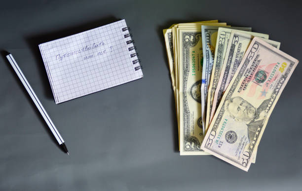 dollar bills, notebook and pen on a gray background