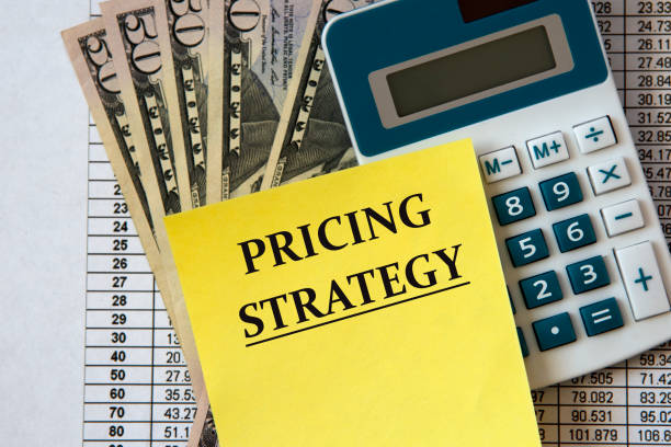 PRICING STRATEGY - words on a white sheet of paper on the background of a calculator and banknotes. Business and finance concept