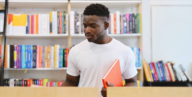 Young African student in a university library, studying with dedication, showcasing modern academic commitment.
