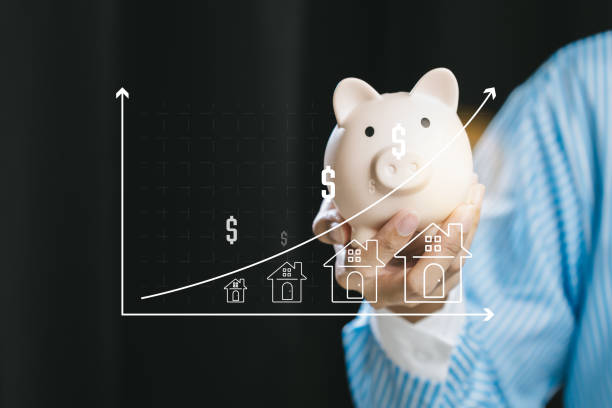 A person holds a piggy bank with a graph in the background representing financial growth in the housing market. Ideal for finance concepts.