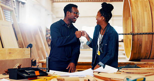 Fist bump, happy and woodworker with manager in workshop for furniture, process or manufacturing. Partnership, partnership and carpenter with supervisor in warehouse for timber material production.